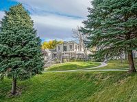 Charming residence surrounded by lush greenery, featuring a beautifully landscaped yard and mature trees in a tranquil setting.