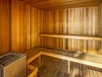 Inviting wooden sauna room with sleek benches and a state-of-the-art heater, offering a luxurious relaxation experience.