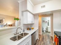 Bright and modern kitchen with sleek countertops, stainless steel appliances, and elegant cabinetry, leading to a stylish bathroom view.