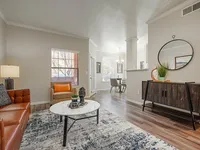 Inviting living space with elegant decor, featuring a cozy sofa, stylish armchair, chic coffee table, and a modern dining area, boasting abundant natural light and a warm, welcoming atmosphere.