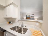Modern kitchen with sleek countertops, double sink, and elegant cabinetry, offering a glimpse into a cozy, art-adorned living space.