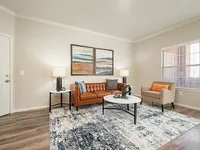 Chic living room with a stylish leather sofa, modern art, and ample natural light for a cozy atmosphere.