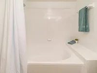 Elegant bathroom featuring a pristine white tiled bathtub with plush teal towels and a serene ambiance.