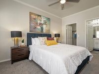 Inviting bedroom with elegant decor, stylish art, and cozy bedding, adjacent to a modern en-suite bathroom.