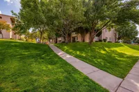 Charming apartment exterior with lush green lawns and mature trees, creating a serene and inviting pathway to your new home.