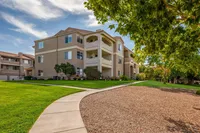 Inviting apartment complex with shaded walkways, manicured lawns, and modern architecture under a clear blue sky.