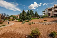 Beautiful apartment complex surrounded by lush greenery, manicured landscaping, and scenic mountain views under a vibrant blue sky.