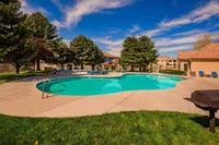 Inviting outdoor pool surrounded by lush greenery and comfortable lounge chairs under a clear blue sky.
