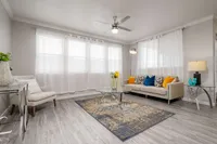 Bright and welcoming living room with large windows, modern furniture, vibrant cushions, and elegant decor.