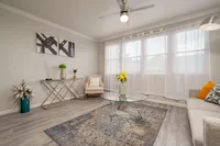Bright and modern living room with elegant decor, featuring a stylish glass coffee table, cozy seating, and large windows for natural light.