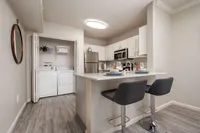 Chic apartment kitchen with modern appliances, elegant breakfast bar, and in-unit laundry for comfortable living.