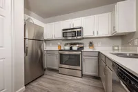 Modern kitchen with sleek stainless steel appliances and elegant white cabinetry, featuring ample counter space and stylish wood flooring.
