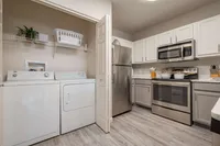 Elegant kitchen with modern stainless steel appliances, sleek cabinetry, and a convenient laundry nook, perfect for contemporary living.