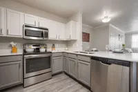 Modern kitchen with sleek stainless steel appliances, elegant gray cabinetry, and chic lighting, featuring a spacious countertop perfect for entertaining.