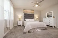 Elegant bedroom featuring a plush gray headboard, soft lighting, and crisp white furnishings creating a serene retreat.