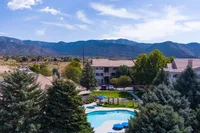 Scenic apartment complex with a sparkling pool, set against stunning mountain views and lush greenery.