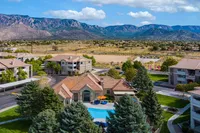 Stunning aerial view of elegant apartment complex surrounded by lush greenery and set against a breathtaking mountain backdrop. Features a luxurious swimming pool and beautifully landscaped grounds.