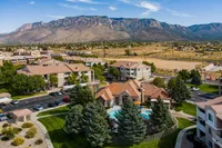 Vibrant apartment community nestled against stunning mountains, featuring lush landscaping and a luxurious pool area.