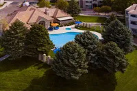 Charming residential complex with a sparkling blue pool, surrounded by lush greenery and spacious outdoor seating area.