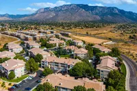 Vibrant aerial view of a serene residential community nestled between lush greenery and majestic mountains.