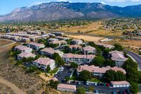 Stunning aerial view of modern apartment complex nestled in picturesque landscape with mountain backdrop and vibrant greenery.
