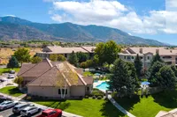 Scenic apartment complex with a sparkling pool and lush landscaping, set against a backdrop of majestic mountains.