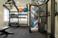 Modern fitness center featuring state-of-the-art gym equipment, colorful geometric accent wall, and ample natural light.