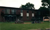 Inviting apartment complex featuring lush green lawns, picnic tables, and a charming outdoor swing.
