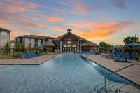 Luxurious apartment complex with a resort-style pool, elegant clubhouse, and vibrant sunset backdrop.