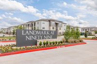 Chic exterior view of Landmark at Ninety Nine apartments with inviting landscaping and modern architecture set against a vibrant blue sky.