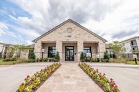 Charming stone facade of an apartment complex, beautifully adorned with vibrant flowers and lush greenery.