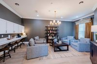 Elegant living space with modern gray seating, chic chandelier, spacious counter seating, and stylish shelving.