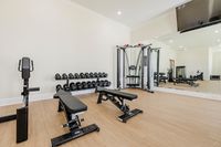 Modern fitness center with sleek wooden floors, complete with exercise machines and free weights, offering a stylish workout environment.