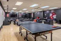 Modern recreation lounge with ping pong table, comfortable seating, and multiple flat-screen TVs.