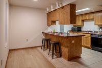 Warm kitchen area with wooden cabinets, a breakfast bar with two stools, and modern appliances.