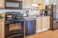 Kitchen Modern kitchen with sleek black appliances, wooden cabinets, and stylish countertops.