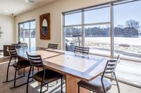 Community Lounge Sunlit conference room with a wooden table and black chairs overlooking a snowy landscape.