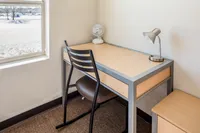 Desk Bright corner with a wooden desk, modern chair, lamp, and small fan near a sunny window.