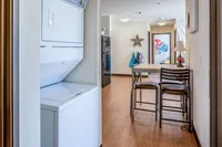 In-Unit Laundry Stylish apartment hallway featuring in-unit laundry, dining area with modern furnishings, and artistic decor.