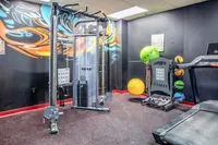Modern fitness room featuring colorful gym equipment, sleek machines, and motivational art on the walls.