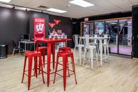 Bright lounge area with red and white bar tables and stools, featuring university-themed decor.