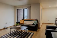 Modern living room with cozy black sofa, colorful throw pillows, and natural light from large patio window, perfect for relaxation and inspiration.