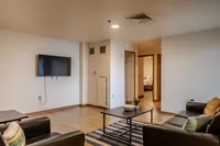Inviting modern living room with cozy seating, stylish decor, and a sleek wall-mounted TV, perfect for relaxation.