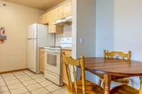 Charming kitchen with modern appliances, cozy dining area, and warm wooden cabinets, perfect for intimate meals.