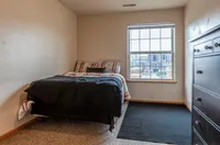 Cozy bedroom with plush bedding and city view, featuring natural light and modern furnishings.