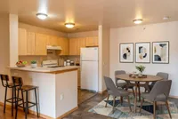 Chic open-plan kitchen and dining area with light wood cabinets, modern decor, and cozy seating for four.
