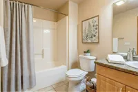 Inviting bathroom featuring a stylish shower curtain, elegant tile flooring, and a charming fern artwork. Includes a sleek countertop with modern stainless fixtures.