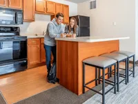 Modern kitchen space featuring sleek wooden cabinetry, a spacious countertop with bar stools, and state-of-the-art appliances, ideal for social gatherings.
