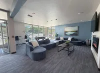 Inviting modern lounge with plush blue seating, a sleek fireplace, and a large window wall offering abundant natural light.