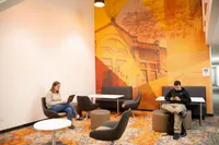 Vibrant lounge area featuring modern furniture, artistic wall mural, and ambient lighting, perfect for relaxing or working.